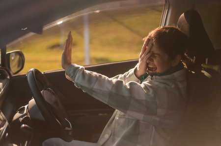 Caucasian woman gets scared while driving with her hands out in front of her before a collisionの写真素材