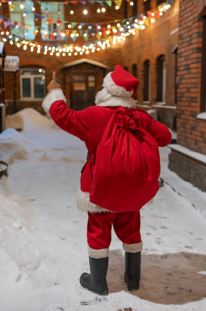 Rear view of santa claus carrying sack of gifts along decorated streetの写真素材