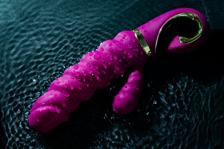 Pink ribbed vibrator in water. Circles on water around toyの写真素材