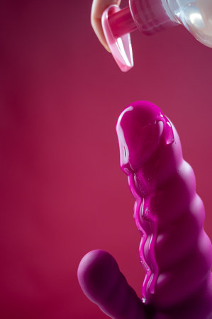 Lube pouring on pink dildo on pink backgroundの写真素材