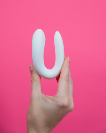 Woman holding white curved object on pink backgroundの写真素材