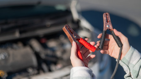 Woman holding clamps for charging a car batteryの写真素材