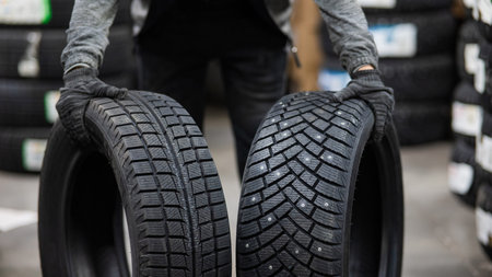 Mechanic keeps new summer and winter car tires in the garage. Comparison of wheels for different...