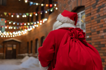 Rear view of santa claus carrying sack of gifts along decorated streetの写真素材