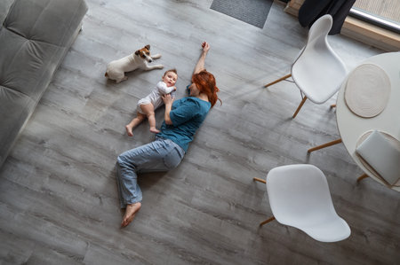 Top view of caucasian woman lying on floor with newborn son and jack russell terrier dogの写真素材