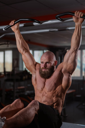 A Caucasian man hangs on a horizontal bar and raises his legs. Vertical photoの写真素材