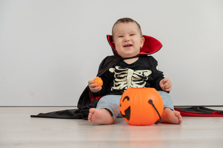 Cute boy in halloween costume holding candy basket on white backgroundの写真素材