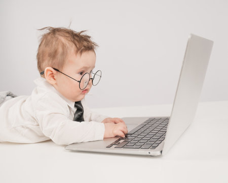 Cute baby in glasses and suit working on laptopの写真素材