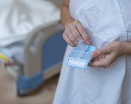 Close up of hands. Woman holding pillbox in hospitalの写真素材