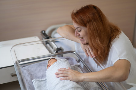 A young mother admires her newborn son in the maternity hospitalの写真素材