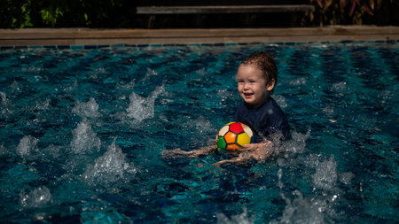 Caucasian one year old boy playing ball in swimming poolの写真素材