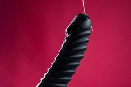 Lube pouring on black object on pink backgroundの写真素材