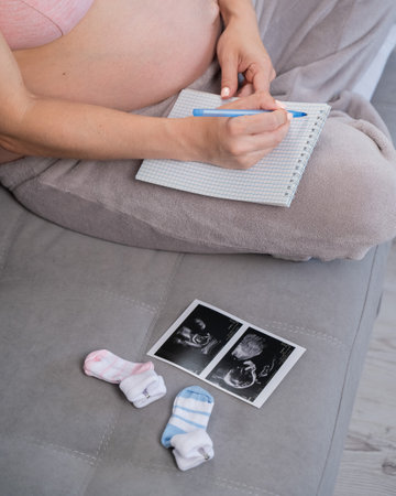 Pregnant woman takes notes in a notebookの写真素材