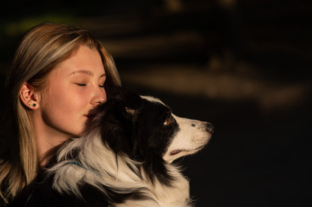 Young Caucasian woman hugging her border collie dog while walking in the parkの写真素材