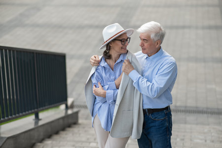 An elderly man puts his jacket on a woman. Romantic relationships of mature peopleの写真素材