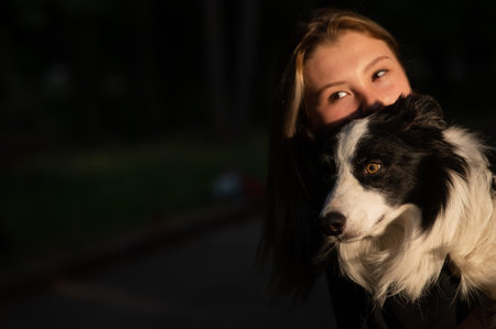 Young woman hugging her border collie dog while walking in the parkの写真素材