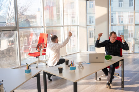 Two Caucasian men celebrate success at workの写真素材