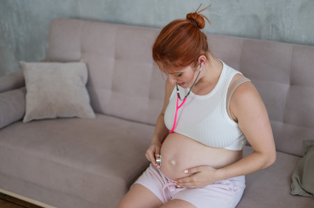 A pregnant woman listens to her babys pulse using a phonendoscopeの写真素材