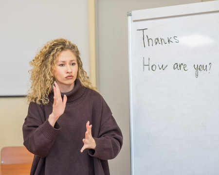 Caucasian female teacher communicates in Russian sign language with students