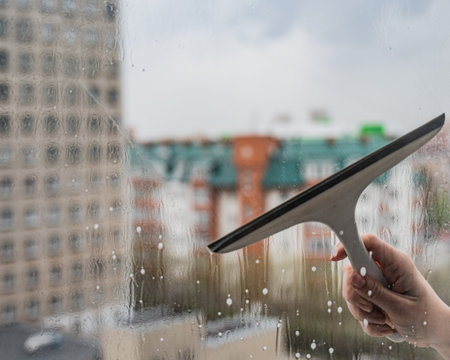 A woman washes a window with a scraperの写真素材
