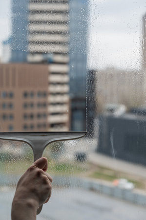 A woman washes a window with a scraperの写真素材