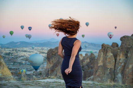 Caucasian woman posing against the backdrop of balloons flying over Cappadocia at sunriseの写真素材