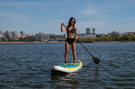 Caucasian woman riding a SUP board on the lake. Summer sport