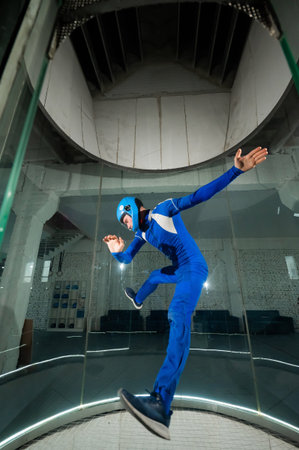A man in overalls and a protective helmet enjoys flying in a wind tunnel. Free fall simulator.