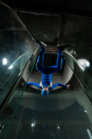 A man in overalls and a protective helmet enjoys flying in a wind tunnel. Free fall simulator.の写真素材