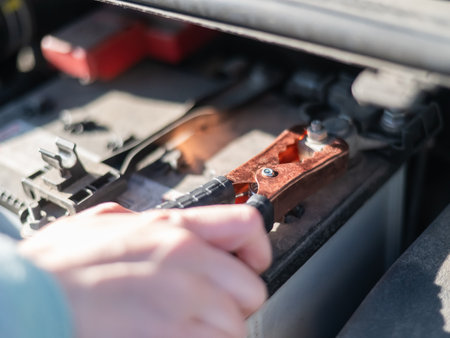 Woman holding clamps for charging a car batteryの写真素材