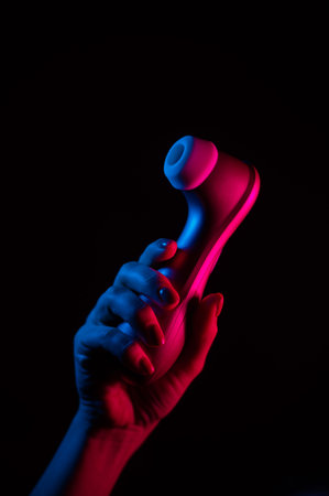 Woman holding vacuum clitoral vibrator under neon light