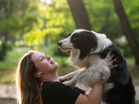Young Caucasian woman hugging her border collie dog while walking in the parkの写真素材
