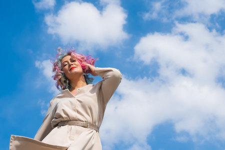 A woman with colored hair walks outdoors. Portrait of a girl against the blue skyの写真素材