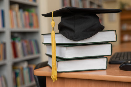 Graduation cap on a stack of books in the libraryの写真素材