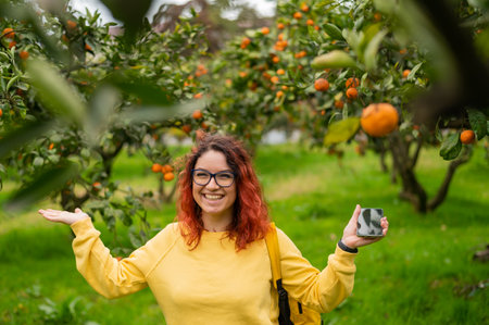 Red-haired smiling woman stands in the tangerine gardenの写真素材
