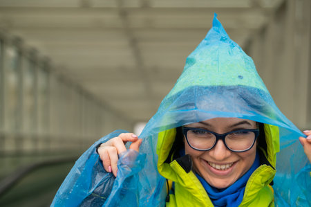 Portrait of a smiling woman with glasses wearing a raincoat outdoorsの写真素材