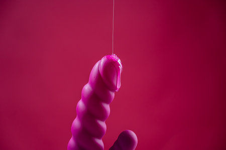 Lube pouring on pink dildo on pink backgroundの写真素材