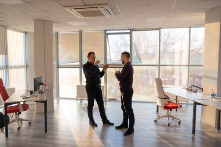 Two Caucasian men talking at work in the officeの写真素材