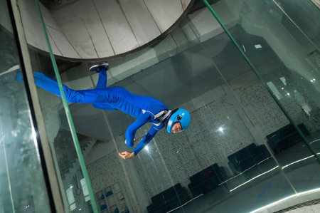 A man in overalls and a protective helmet enjoys flying in a wind tunnel. Free fall simulator.