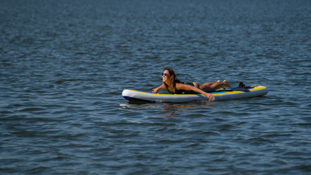 Caucasian woman posing on a SUP board. Summer sport