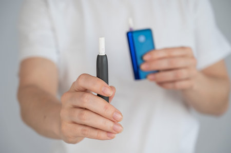 A woman compares two different tobacco heating systems. Electronic cigarette