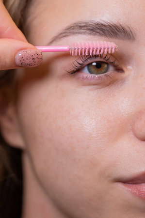 Caucasian woman brushing her eyelashes after laminationの写真素材