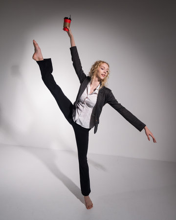 Barefoot ballerina in business suit dancing with a cup of coffee on a white backgroundの写真素材