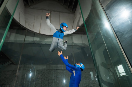 A male instructor teaches a woman how to fly in a wind tunnel. Free fall simulator
