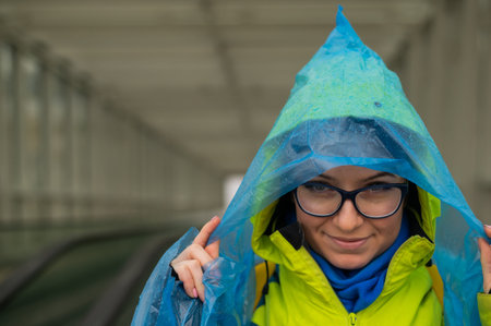 Portrait of a smiling woman with glasses wearing a raincoat outdoors