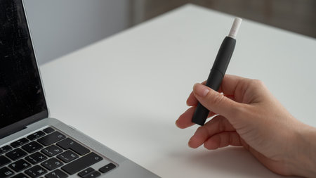 A woman smokes an electronic cigarette while working on a laptop. Tobacco heating systemの写真素材