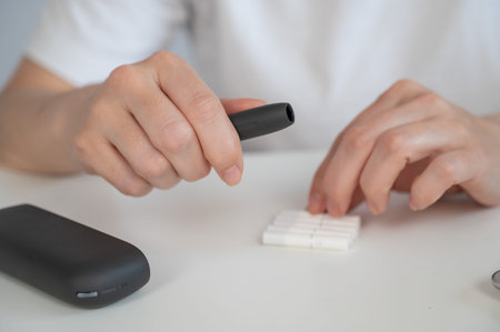 A woman inserts a cigarette stick into a tobacco heating system.