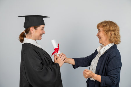 An elderly Caucasian woman presents a diploma to a graduateの写真素材