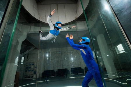 A male instructor teaches a woman how to fly in a wind tunnel. Free fall simulator