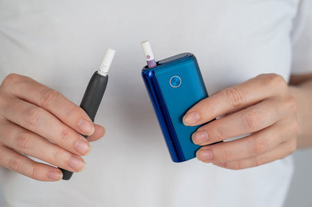 A woman compares two different tobacco heating systems. Electronic cigarette